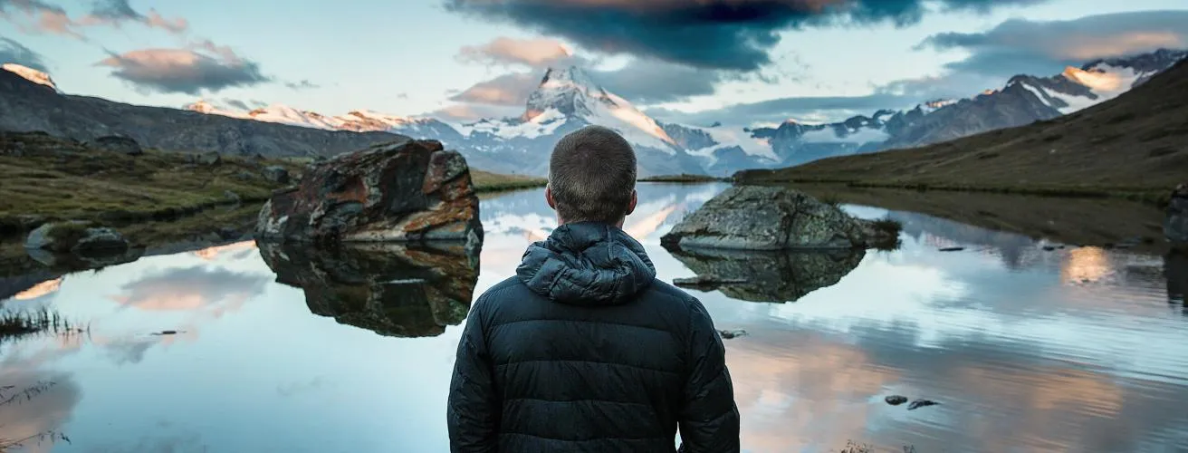 Man overlooking lake towards mountains.
