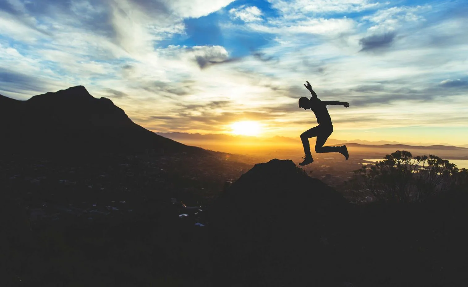 Person jumping joyfully under a bright sky.